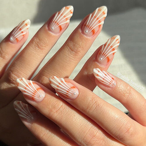 Simple long almond-shaped white seashell nails above a nude base color and adorned with a pearl on the top