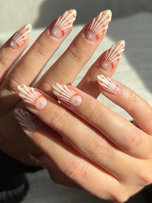 Simple long almond-shaped white seashell nails above a nude base color and adorned with a pearl on the top