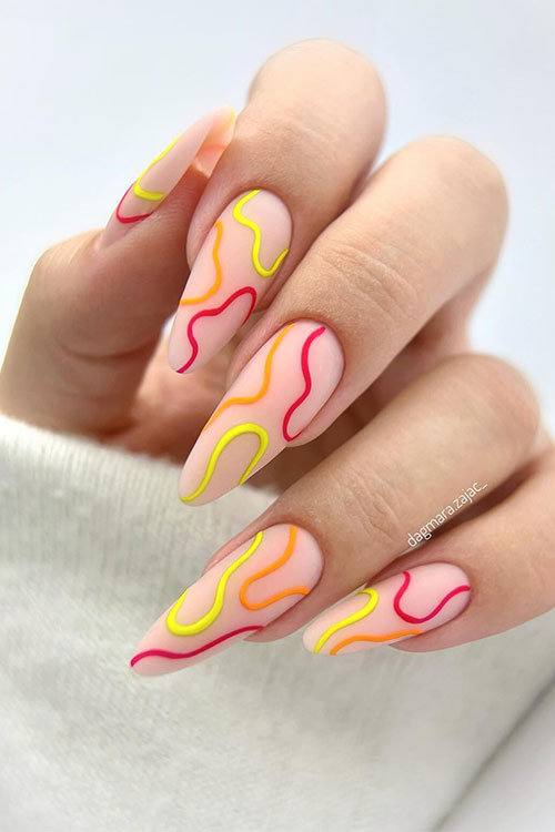 Cute long almond-shaped nude nails adorned with neon yellow, neon orange, and neon strawberry swirls