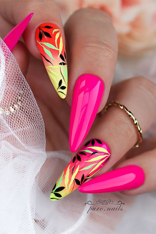 Long almond-shaped neon pink summer nails with two accent ombre nails adorned with black, yellow, and green leaf nail art