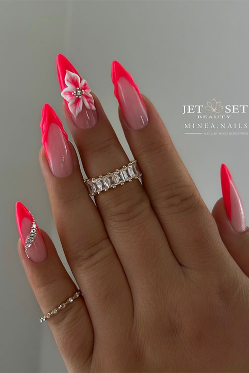 Long almond-shaped neon red French tip nails adorned with a white flower and some silver rhinestones on two accent nails