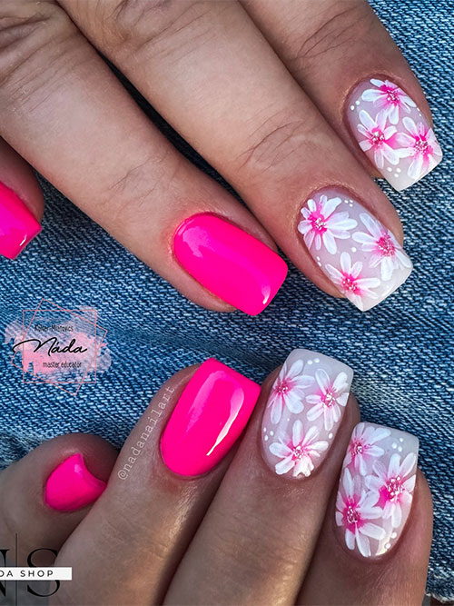 Medium neon pink nails with two accent milky white nails adorned with daisy flowers