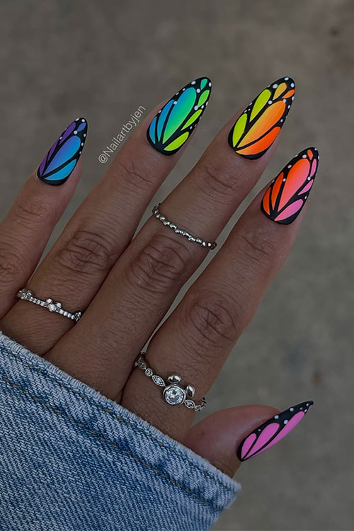 Ombre multicolored neon nails adorned with black butterfly wings nail art decorated with white dots