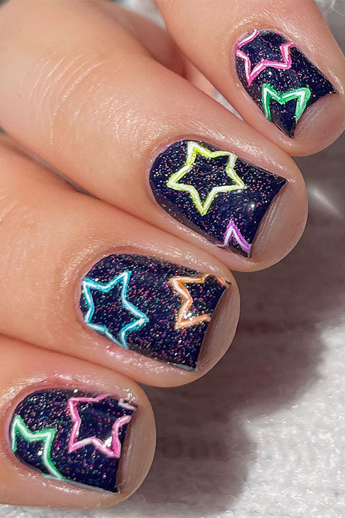 Short sparkly black nails decorated with micro multicolored glitter then the nails adorned with neon multicolored stars