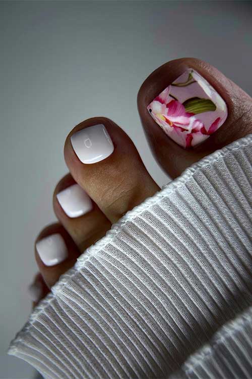 Glossy white toenails with a subtle pink big toenail decorated with pink flowers and green leaves