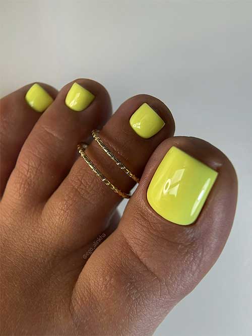 Bright yellow toenails painted with a glossy finish