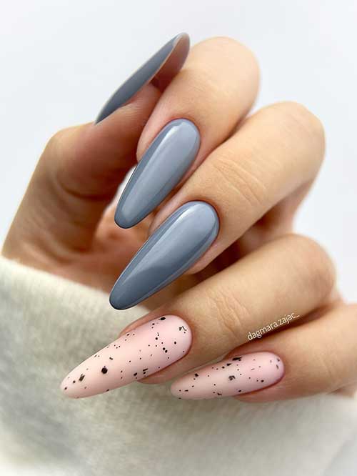 Long almond-shaped gray nails with two accent nude nails decorated with black speckles