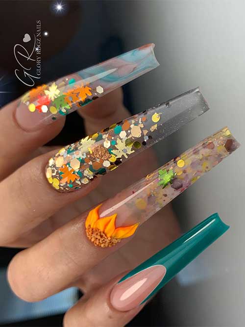 Long coffin-shaped clear nails decorated with autumnal-colored glitter and maple leaf glitter