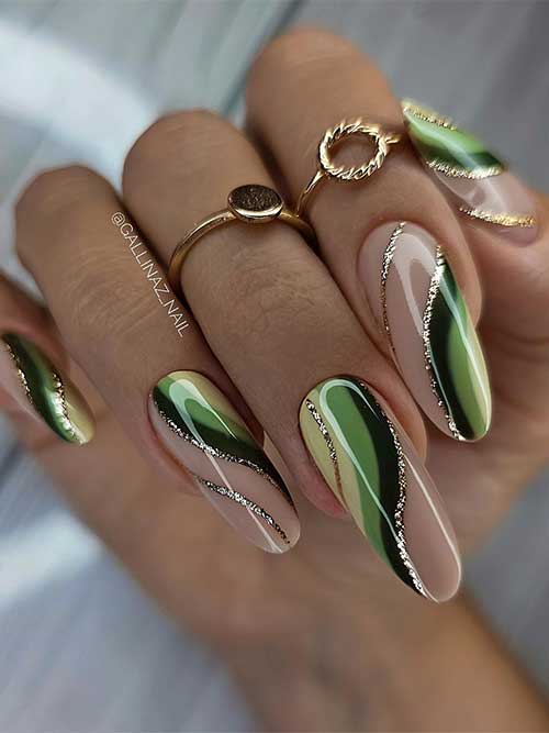 Long nude nails adorned with different green colors swirls and decorated with gold glitter swirls