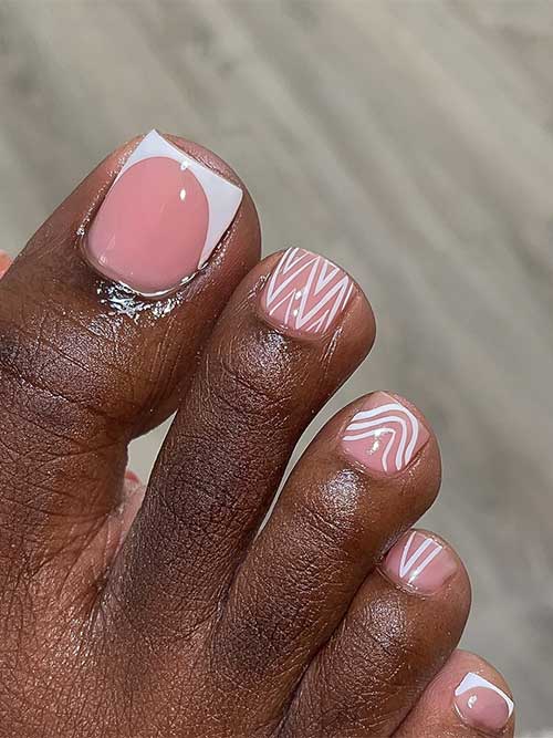 Nude toenails featuring two white French tips, line nail art accents, and a nude accent nail for a chic look.