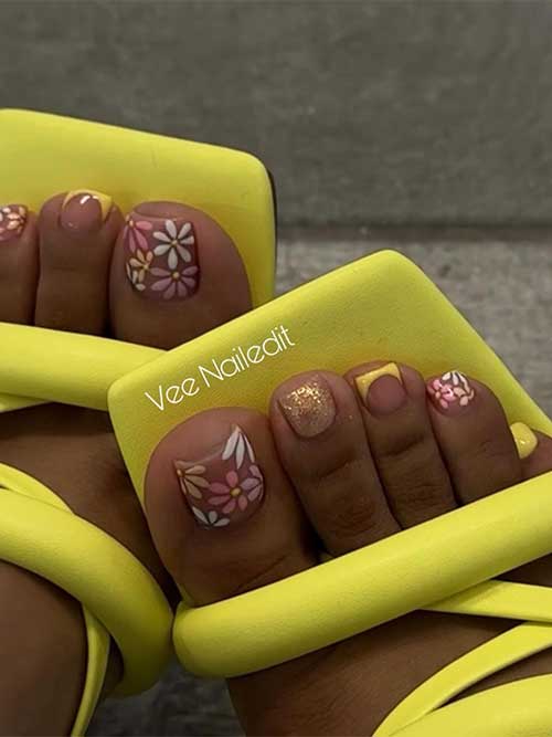 Spring pedicure design with colorful floral toenails, gold glitter, yellow French tip, and a solid yellow accent nail.