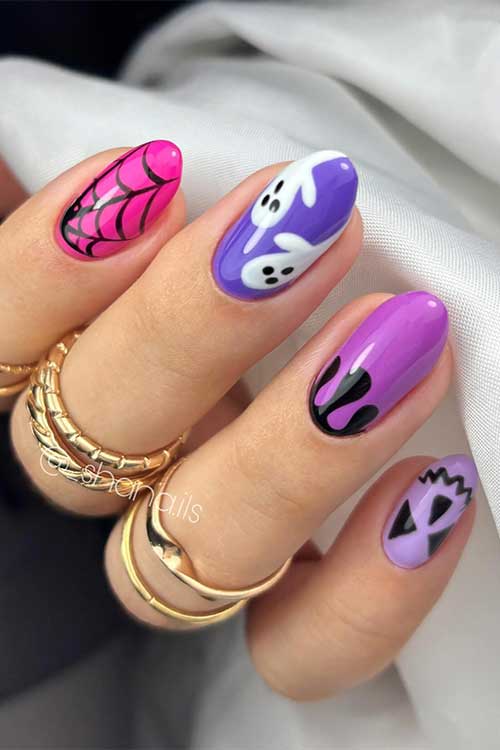 Chic Halloween manicure features different purple and pink nails decorated with ghosts, drip nail art, and cob web