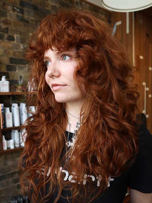 A stylish long shag haircut with copper curls, showcasing vibrant texture and a playful, modern look.