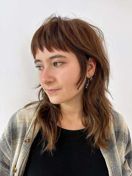 The razored long shag haircut with baby bangs is a trendy option that brings a youthful edge to the classic shag.