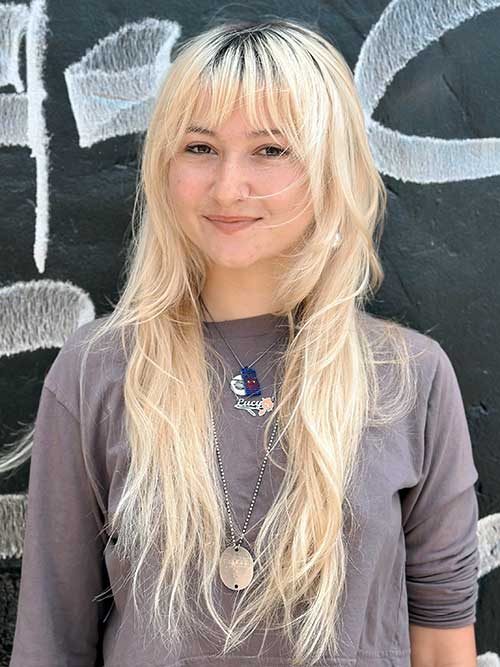 Wispy long blonde shag hairstyle with dark roots, perfect for ladies with thin hair, adding volume and style.