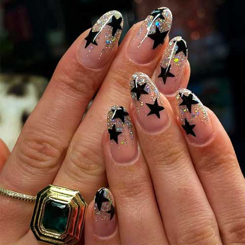 Set of 24 medium almond press-on nails featuring black stars and glossy silver and gold glitter for a sparkly manicure.