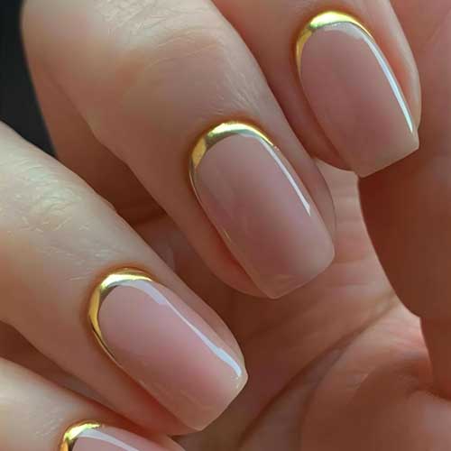 Short square press-on nails featuring a reverse French tip design in nude and gold, glossy finish, 24 reusable acrylic pieces.