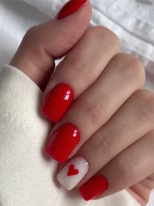 Glossy red acrylic press-on nails with heart designs, perfect for Valentine's Day for a stylish manicure.