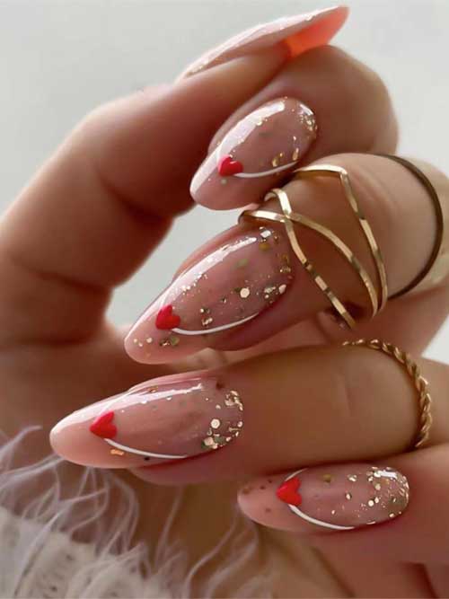 Valentine's Day almond-shaped press-on nails in nude with gold glitter hearts. Easy to apply for a chic and festive look.