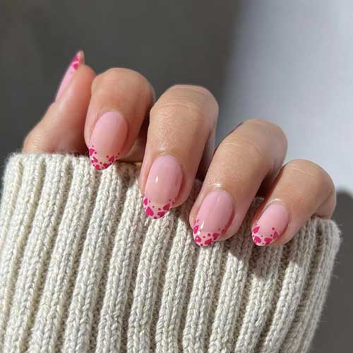 Valentine's-themed medium almond nails featuring French heart tips. Full cover and easy to apply for a stylish manicure.