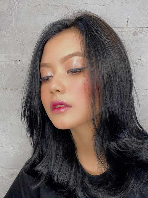 A glowing makeup look with glassy skin achieved by mixing highlighter into foundation for a fresh spring vibe.