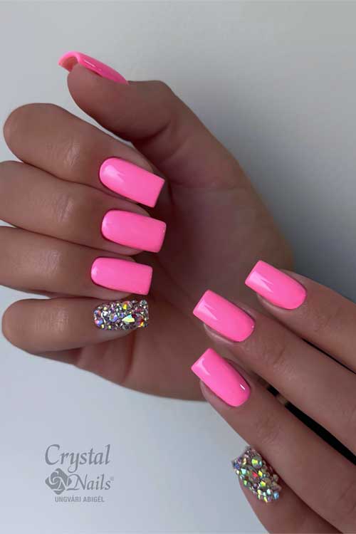 Bright neon pink manicure with glitter accent nails in multi-colored hues, radiating energy and playful glamour.