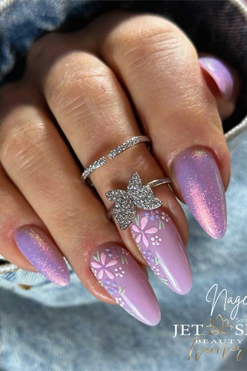 Elegant almond-shaped nails in purple and pink gradient with shimmer, featuring white flowers, butterflies, and a silver ring.