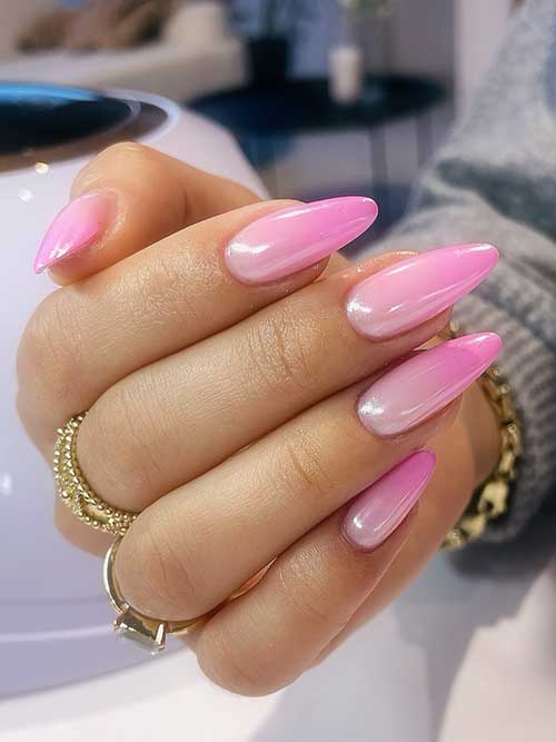 Long almond-shaped nails transition from pastel pink to vibrant magenta, finished with high gloss and paired with gold accessories.